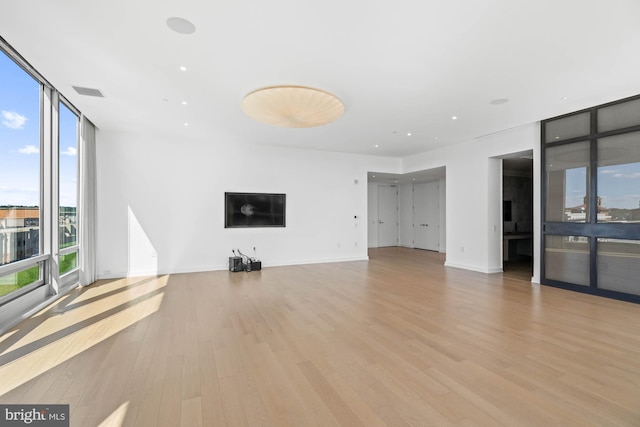 unfurnished living room featuring expansive windows and light wood-type flooring