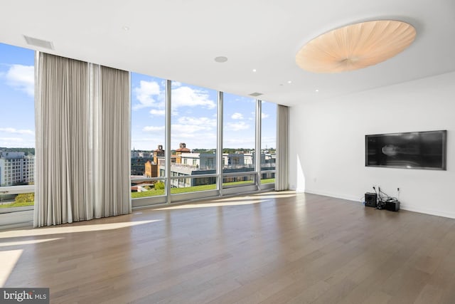 unfurnished living room featuring floor to ceiling windows, plenty of natural light, and hardwood / wood-style flooring