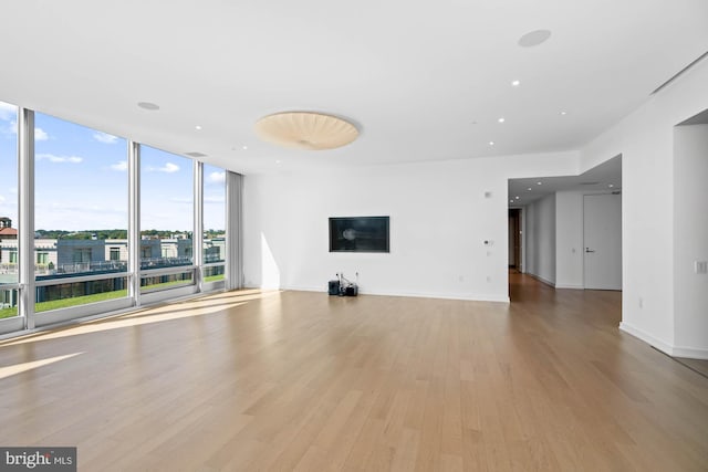 unfurnished living room featuring expansive windows and light hardwood / wood-style flooring