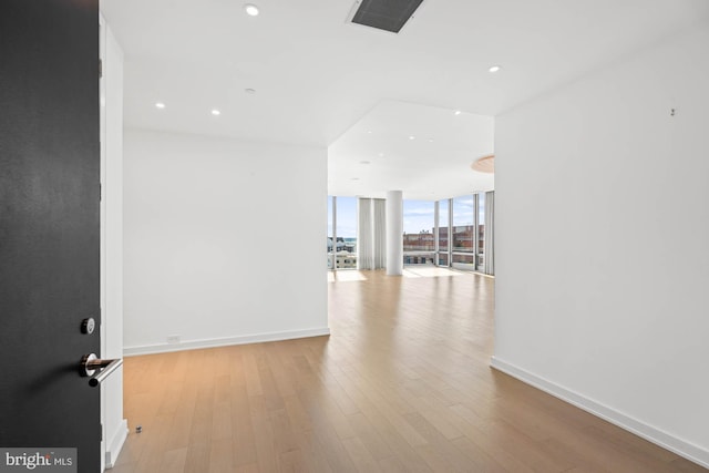 spare room with a wall of windows and light wood-type flooring