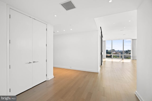 hall featuring light hardwood / wood-style flooring and a wall of windows