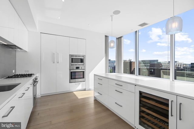 kitchen featuring white cabinets, light wood-type flooring, stainless steel appliances, and wine cooler