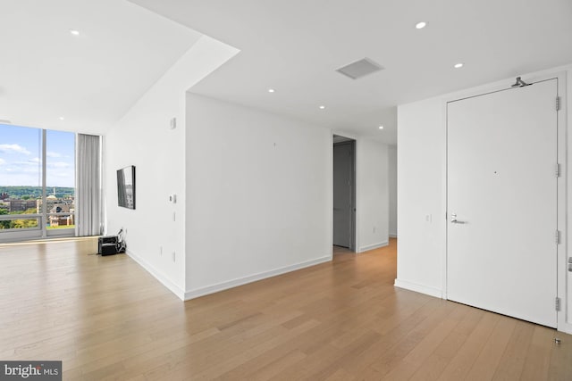 spare room with floor to ceiling windows and light hardwood / wood-style floors