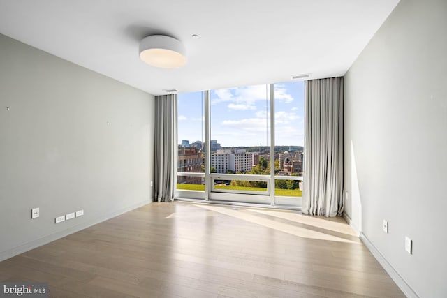 empty room with light wood-type flooring and expansive windows