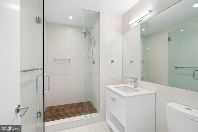 bathroom featuring vanity, a shower with shower door, tile walls, and toilet