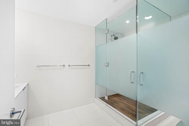 bathroom featuring tile patterned flooring, vanity, tile walls, and a shower with shower door