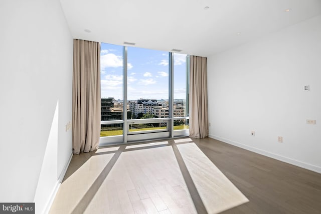 empty room featuring hardwood / wood-style floors and a wall of windows