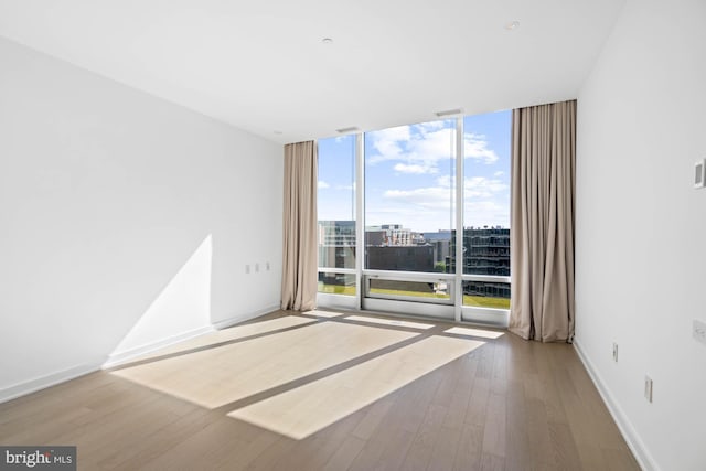 unfurnished room featuring plenty of natural light, expansive windows, and wood-type flooring