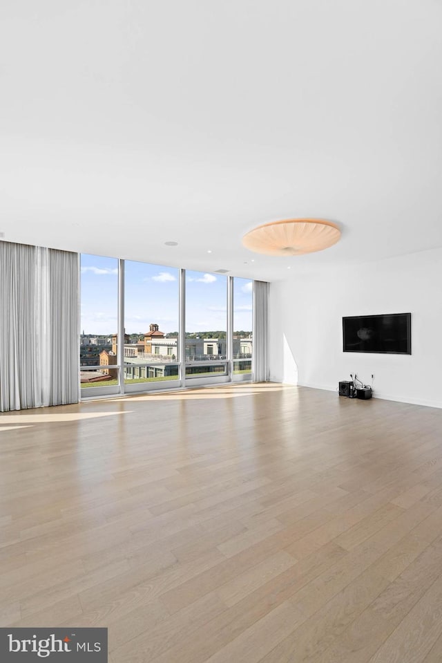 unfurnished living room with light wood-type flooring and floor to ceiling windows