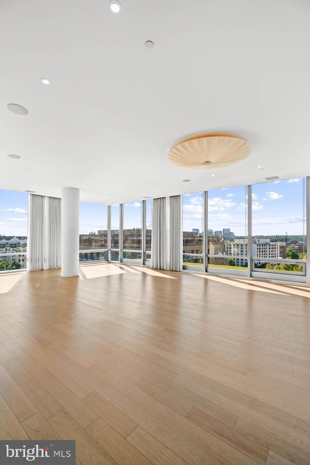 unfurnished room featuring a wall of windows, plenty of natural light, and light hardwood / wood-style floors