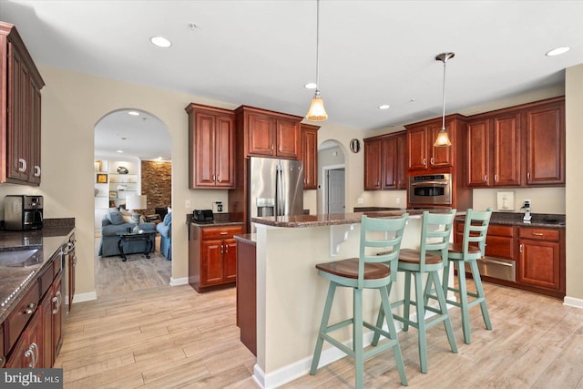 kitchen with decorative light fixtures, light hardwood / wood-style flooring, stainless steel fridge, and a kitchen island