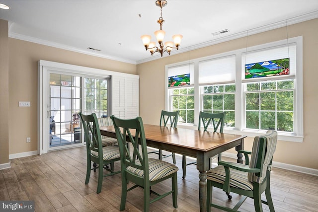 dining area with light wood-type flooring, an inviting chandelier, and crown molding