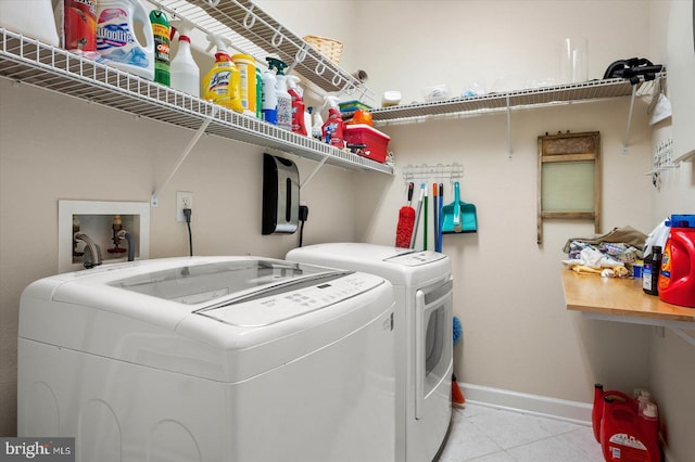 laundry area with independent washer and dryer and light tile patterned flooring