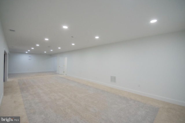 below grade area featuring baseboards, visible vents, light colored carpet, and recessed lighting