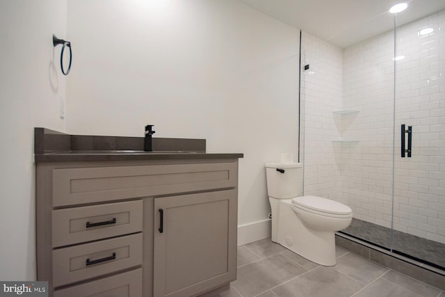 bathroom with toilet, a stall shower, vanity, tile patterned flooring, and baseboards