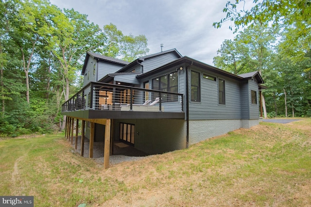 rear view of property featuring a lawn and a wooden deck