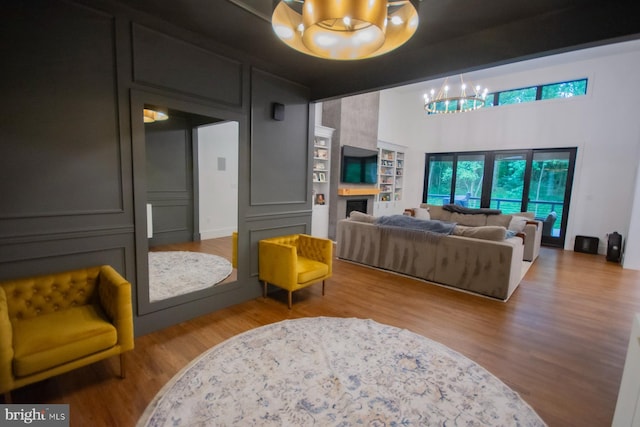 living area with a large fireplace, light wood finished floors, and an inviting chandelier