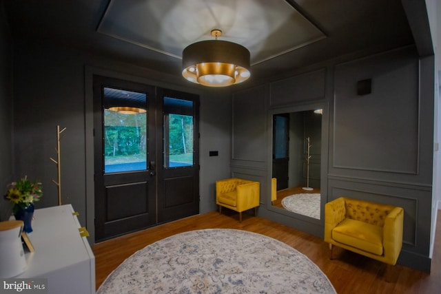 foyer entrance featuring a decorative wall, wood finished floors, and french doors