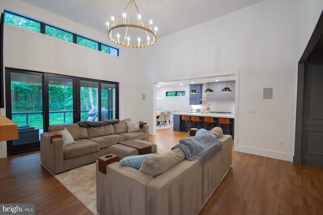 living room with a notable chandelier, plenty of natural light, wood finished floors, and baseboards