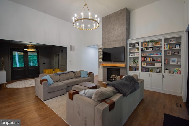 living room with a high ceiling, visible vents, a fireplace, and wood finished floors