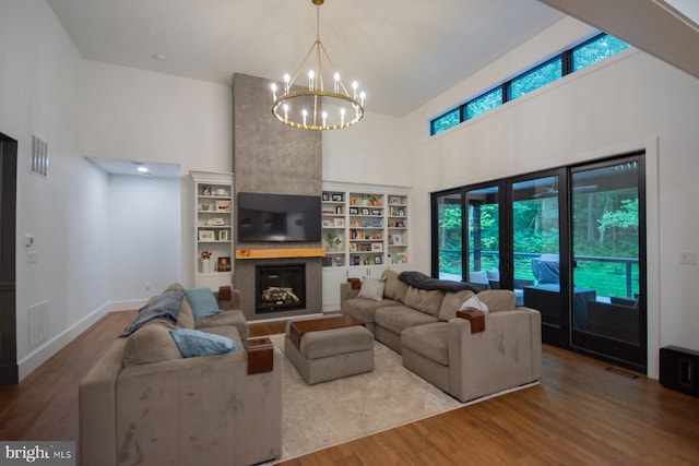 living room featuring visible vents, a fireplace, a high ceiling, and wood finished floors