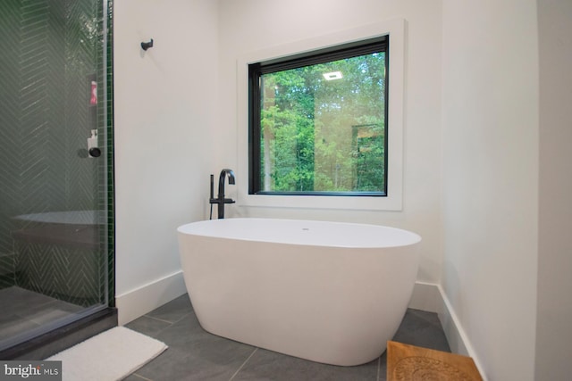 full bathroom featuring a freestanding bath, tiled shower, tile patterned flooring, and baseboards