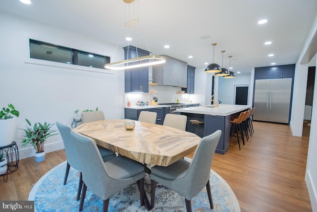 dining area featuring baseboards, light wood finished floors, and recessed lighting