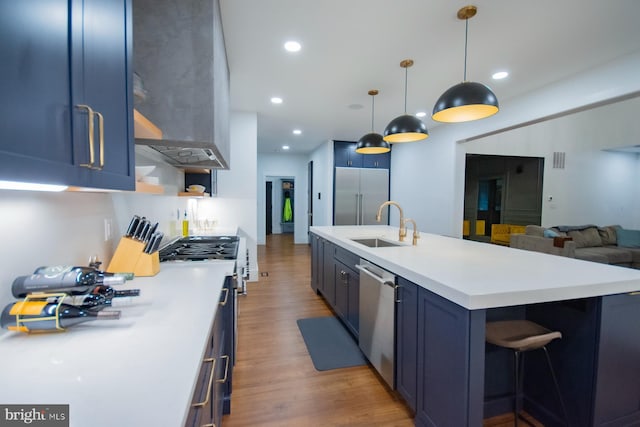 kitchen with stainless steel appliances, light countertops, a sink, and decorative light fixtures