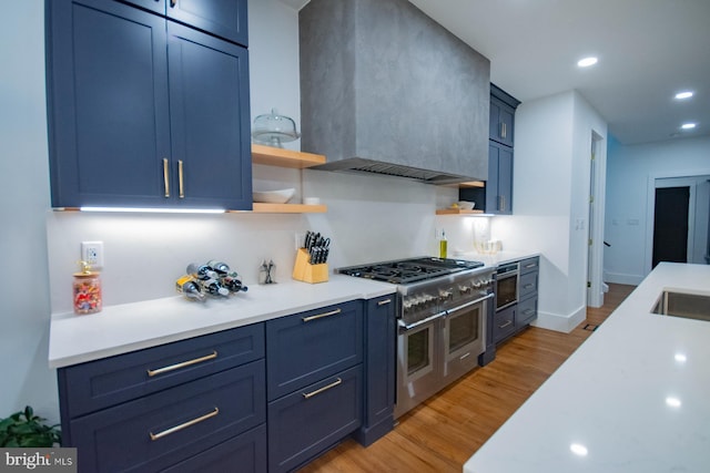 kitchen featuring range with two ovens, custom exhaust hood, light countertops, blue cabinetry, and open shelves