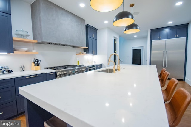 kitchen with a sink, light countertops, range, wall chimney exhaust hood, and a kitchen bar