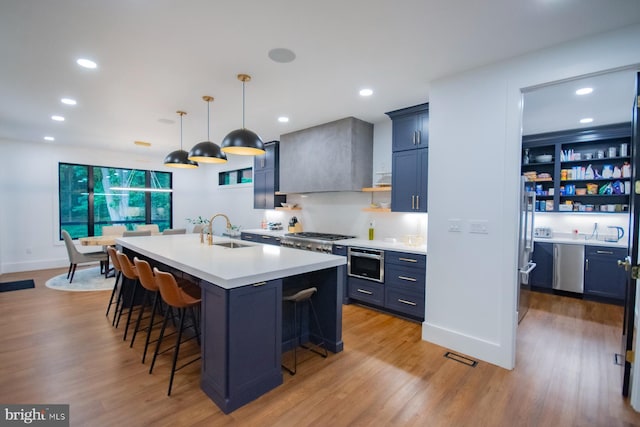 kitchen featuring pendant lighting, a center island with sink, open shelves, light countertops, and a sink