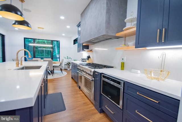 kitchen with open shelves, light countertops, a sink, blue cabinets, and wall chimney exhaust hood