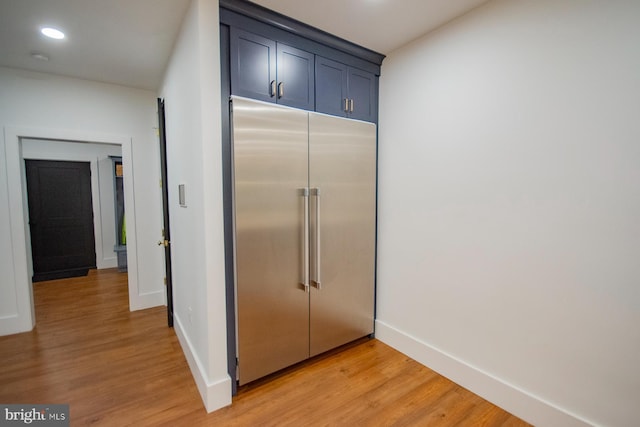 kitchen featuring baseboards, light wood-style flooring, built in refrigerator, blue cabinets, and recessed lighting