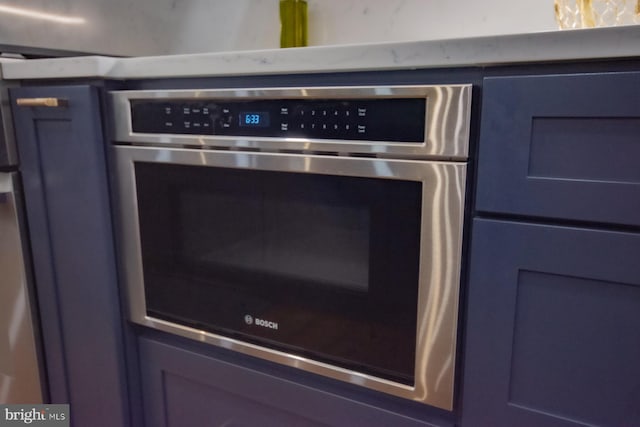 interior details featuring stainless steel oven and blue cabinets