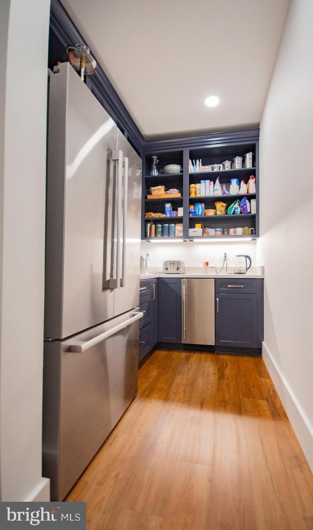 bar featuring light wood finished floors, appliances with stainless steel finishes, recessed lighting, and baseboards