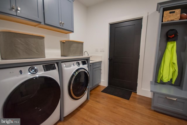 washroom featuring light wood finished floors, independent washer and dryer, and cabinet space