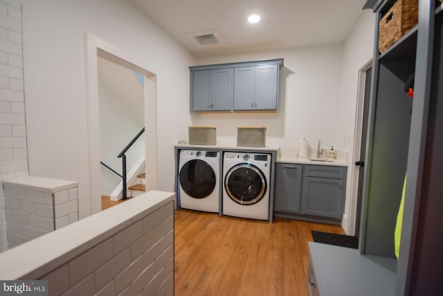 laundry area featuring light wood finished floors, recessed lighting, cabinet space, a sink, and washer and dryer