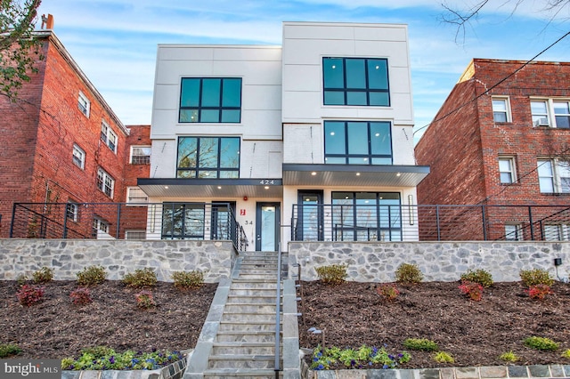 modern home featuring stairs, fence, stucco siding, and covered porch
