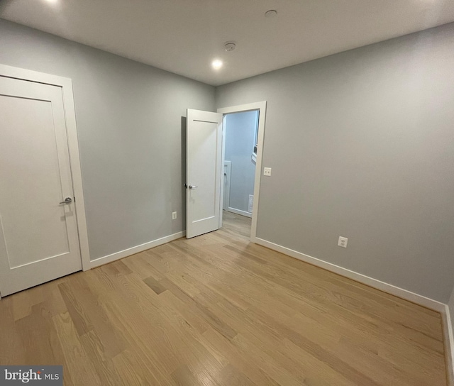 empty room featuring light wood-style flooring, baseboards, recessed lighting, and a smoke detector