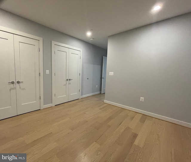 unfurnished bedroom with multiple closets, baseboards, recessed lighting, and light wood finished floors