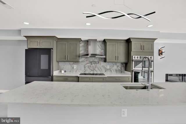 kitchen featuring wall chimney exhaust hood, fridge, stainless steel double oven, a sink, and tasteful backsplash