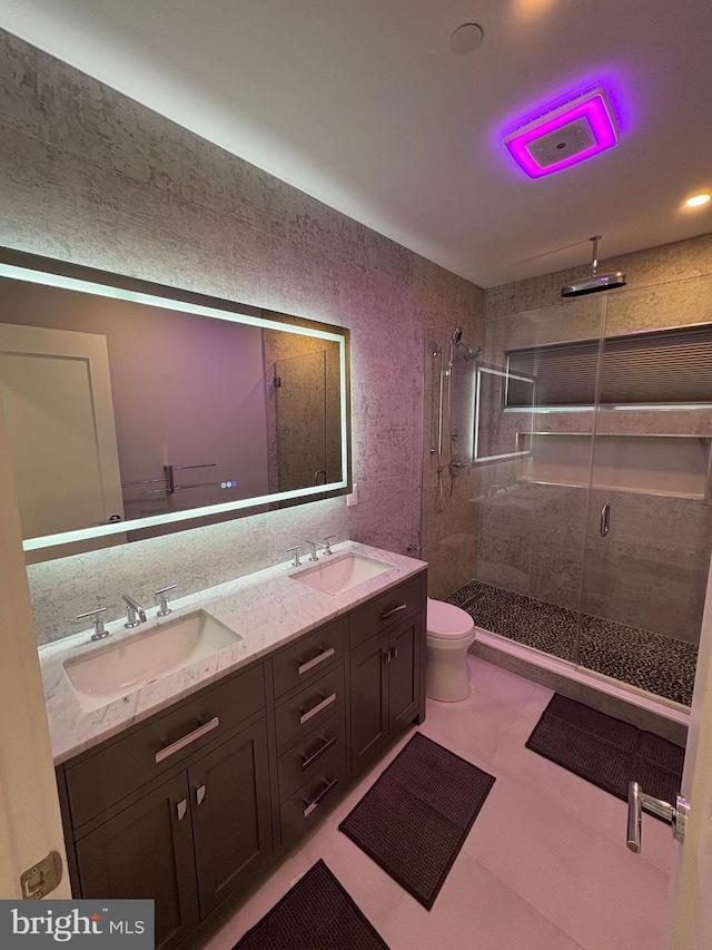 bathroom with a stall shower, double vanity, and toilet