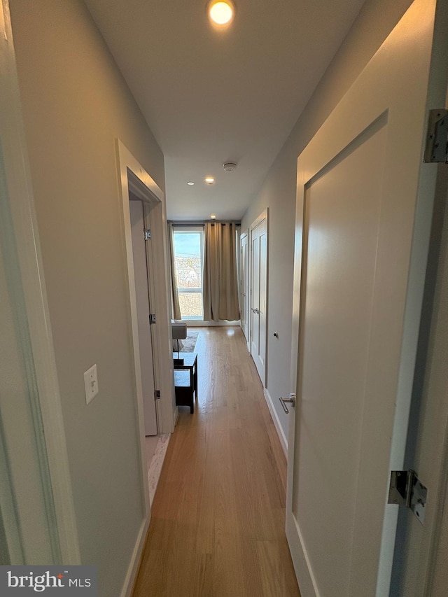 hall featuring light wood-type flooring, baseboards, and recessed lighting