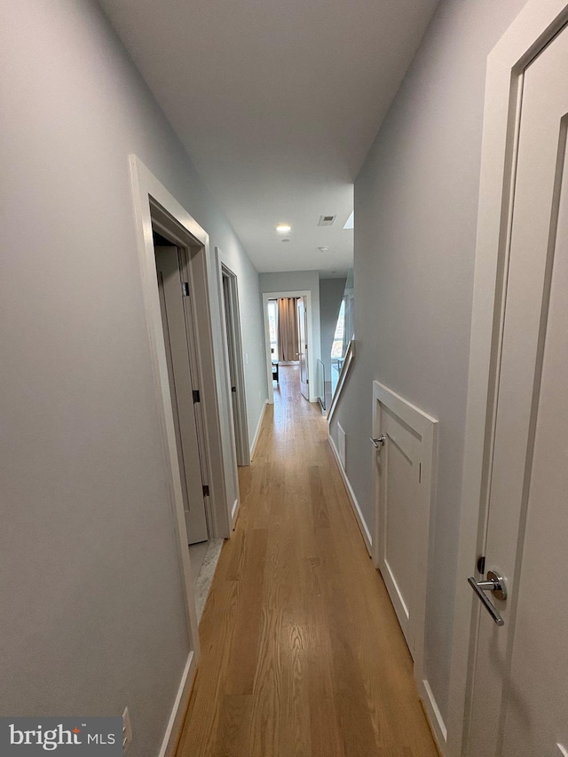 hallway featuring light wood finished floors and baseboards