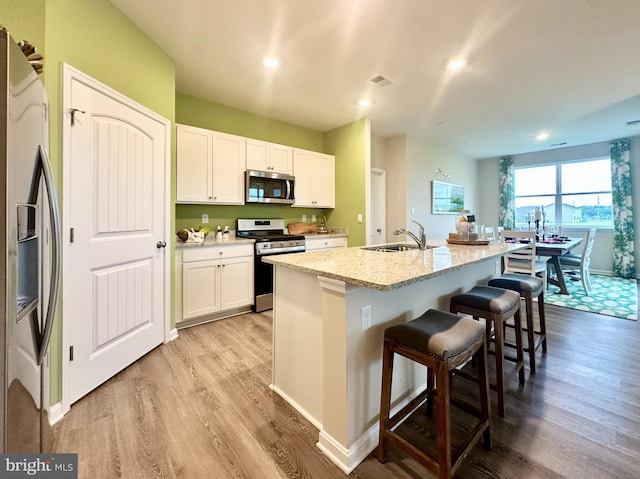 kitchen featuring sink, a breakfast bar area, an island with sink, white cabinetry, and stainless steel appliances