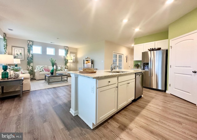 kitchen with sink, white cabinetry, stainless steel appliances, and an island with sink