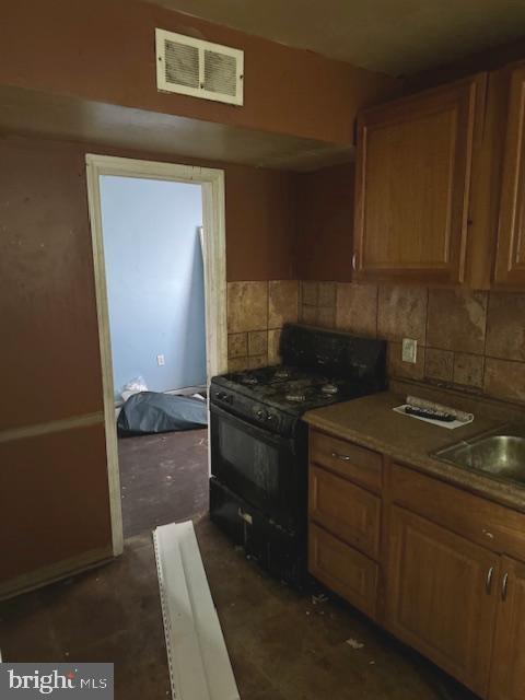 kitchen with decorative backsplash, sink, and black gas range oven