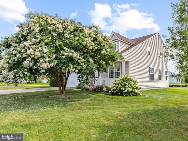 view of side of home featuring a porch, a yard, and a garage