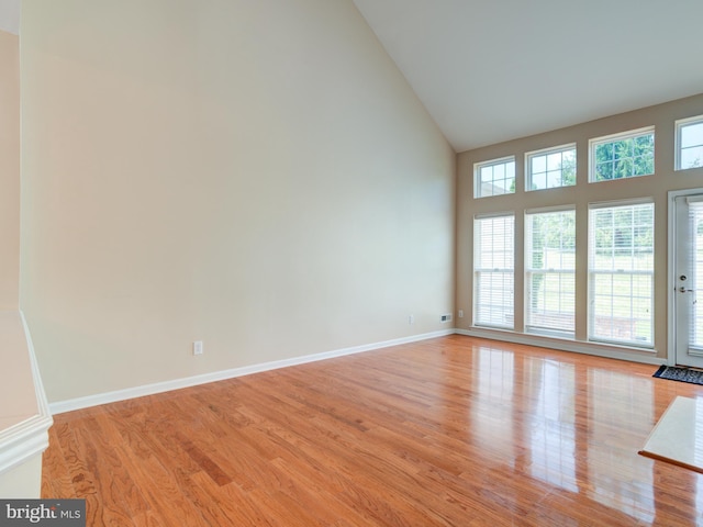 empty room with light hardwood / wood-style floors and a towering ceiling