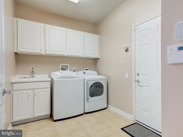 clothes washing area with cabinets, sink, and separate washer and dryer